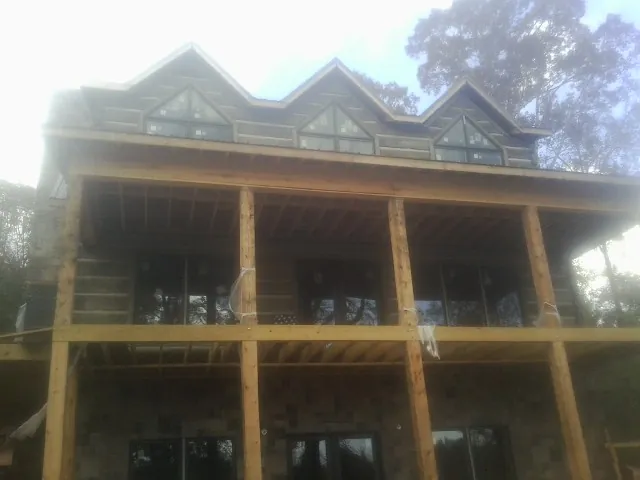 Dormers and porch framing on a large log home under construction — Roof Coating work by our crew in Vass