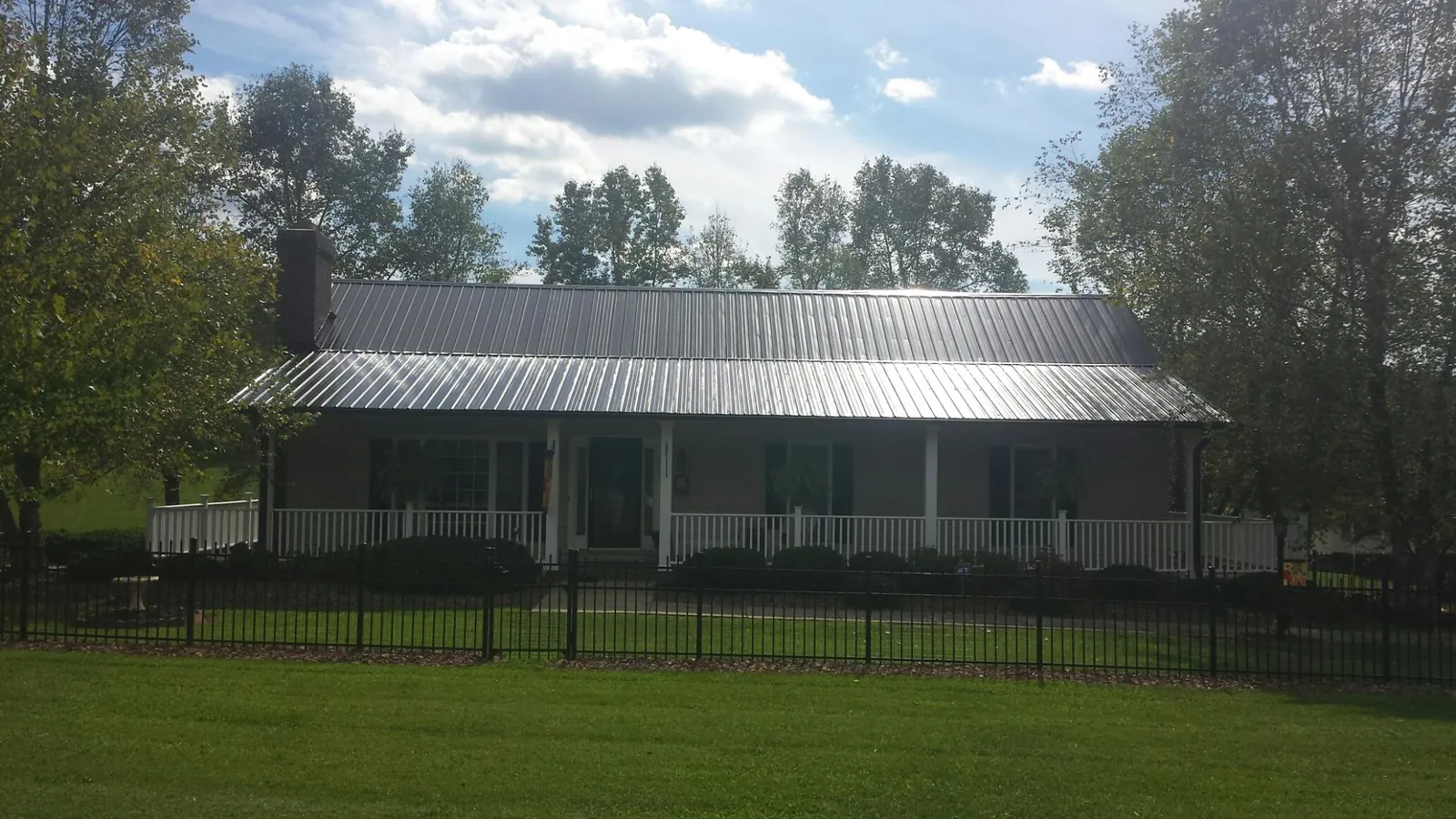 Gray metal roof on a brick ranch with a full width front porch — Gutter Guard Installation work by our crew in Vass