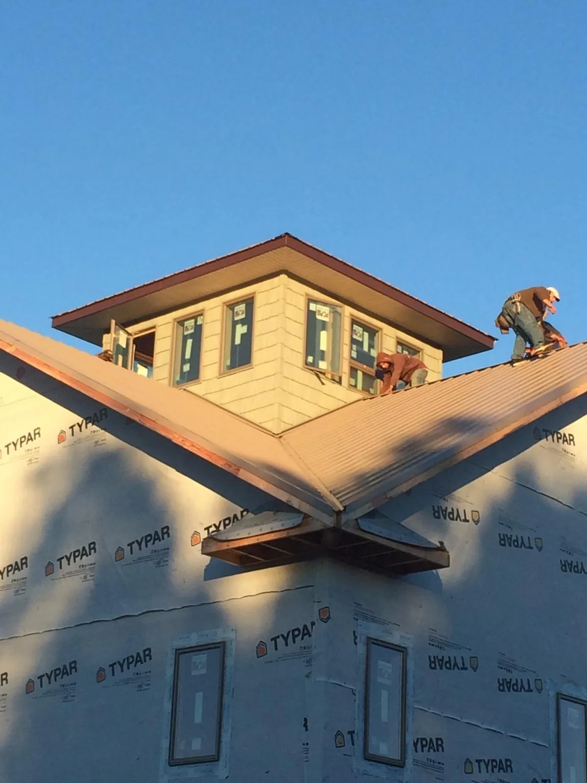 Roofers working around a rooftop cupola on a new metal roof at sunset — Roof Waterproofing in Vass by Roofing Brothers